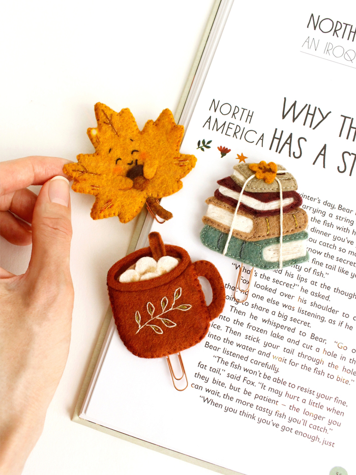 Felt autumn bookmarks shown on an open book with maple leaf design